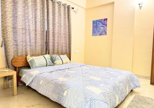 a bedroom with a bed with a blue and white comforter at Evara Grand Vista - Fully Equipped 3BHK near AMB in Hyderabad