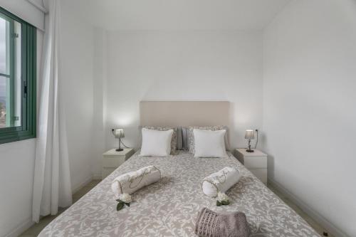 a white bedroom with a bed with shoes on it at Costa Serena in Arona