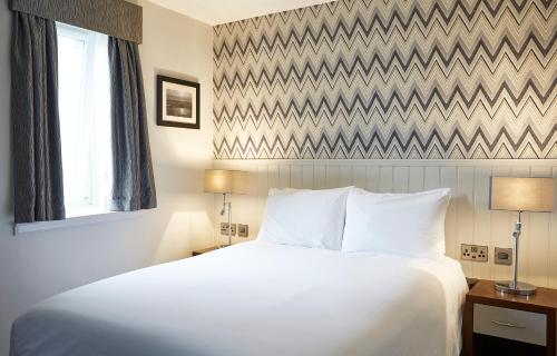 a bedroom with a large white bed and a window at Fishermans Tavern in Dundee