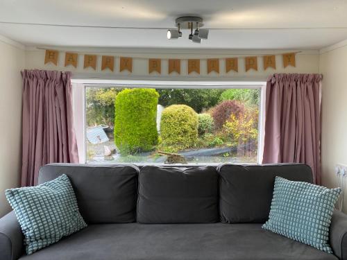 a couch in a living room with a large window at Fabulous Hot Tub with Views! in Llanfair Caereinion