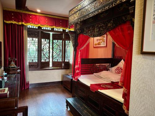 a bedroom with a canopy bed with red curtains at ChengDu Wuhou Temple Han Dynasty Hotel in Chengdu