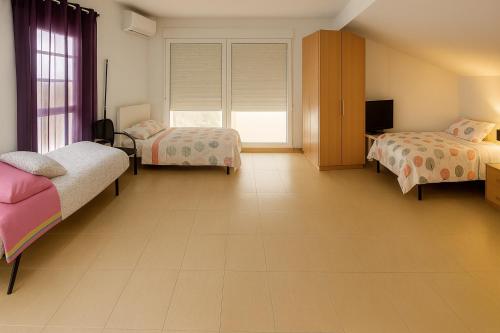 a large room with two beds and a television at Victors Rooms - Habitaciones Privadas en mi Acogedor Chalet in Madrid