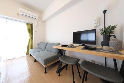 a living room with a desk with a tv and a couch at 宇都宮ハウスリリー in Utsunomiya