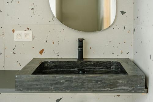 a stone sink in a bathroom with a mirror at La Ferme d'Auwez - Horizon - Gîte 6 pers avec piscines et sauna in Ciney
