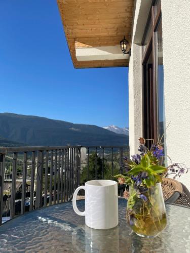 a coffee mug and a vase on a table on a balcony at Hillside Mestia ჰილსაიდ მესტია in Mestia