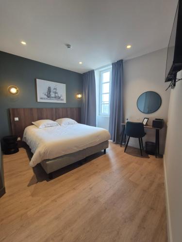 a bedroom with a large bed and a desk with a chair at Hôtel l'Hermine - Vannes Port de plaisance in Vannes