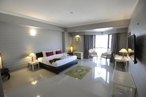 a hotel room with a bed and a table and chairs at Napalai Hotel in Udon Thani