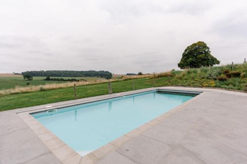 a swimming pool with a view of a field at La Ferme d'Auwez - Horizon - Gîte 6 pers avec piscines et sauna in Ciney
