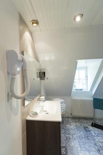 a white bathroom with a sink and a window at LA MAISON DES CHEVAUX in Eu
