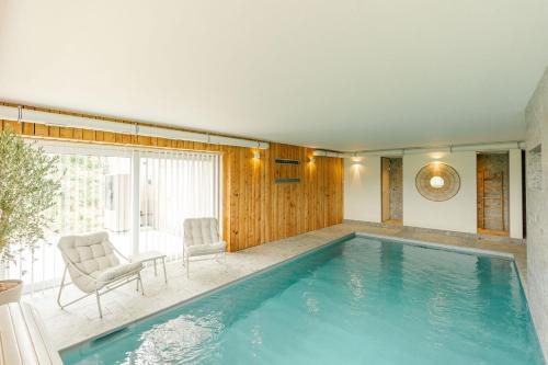 a large swimming pool with two chairs and a table at La Ferme d'Auwez - Horizon - Gîte 6 pers avec piscines et sauna in Ciney