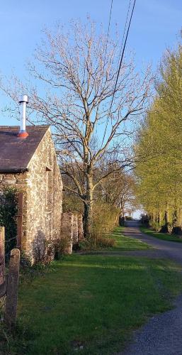 an old stone house with a tree and a road at Barn Retreat with Mountain Views in Athy
