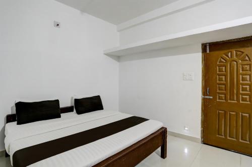 a bedroom with a bed and a wooden door at Hotel O Taaj Inn Guest House in Bhubaneshwar