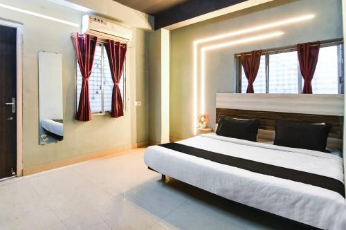 a bedroom with a large bed with red curtains at Hotel O Taaj Inn Guest House in Bhubaneshwar