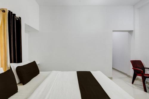 a bedroom with a bed and a red chair at Hotel O Taaj Inn Guest House in Bhubaneshwar