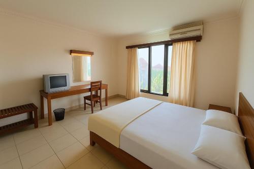 a bedroom with a bed and a desk and a television at Collection O Bali near Bajra Sandhi Monument formerly Hotel Puri Samaritan in Denpasar