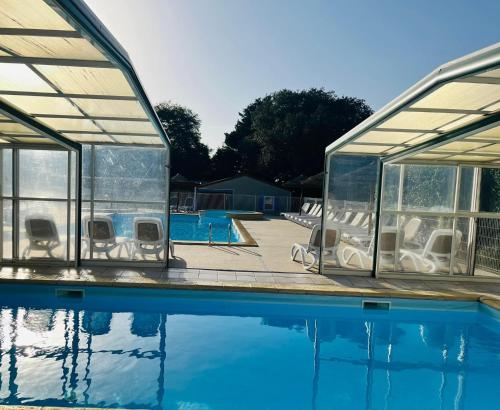 a swimming pool with a pavilion and a house at Camping Le Roc in Vairé
