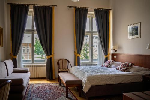 a bedroom with a bed and a couch and windows at Hotel Polonia in Kraków