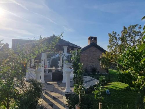 a house with a white porch and a brick building at Pepper Apartman Donji Miholjac in Donji Miholjac