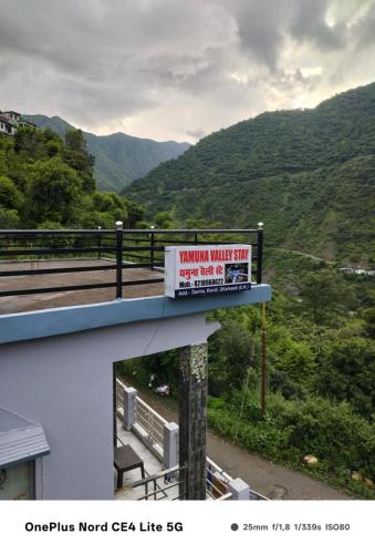 a sign on top of a building with a mountain view at Enjoy Nature at Yamuna Valley Stay in Kandi