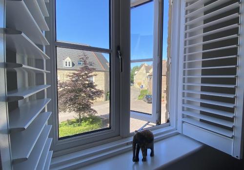 a dog figurine sitting on a window sill looking outside at Modern Town House in Cotswolds - 3 double bedrooms in Witney