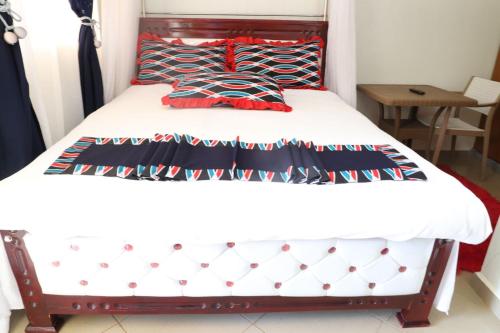 a bedroom with a bed with white sheets and red pillows at Hotel Judith, GULU in Buwate