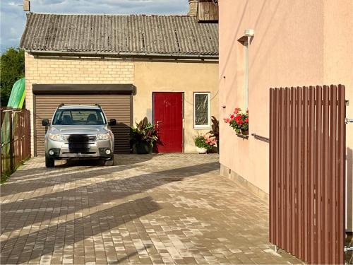 a car parked next to a garage with a red door at Apartment Vainagu street Sigulda in Sigulda