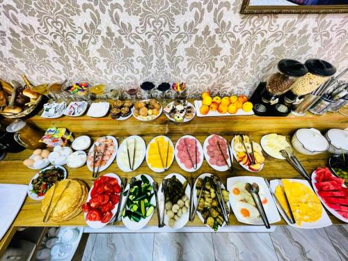 une table remplie de nombreux types de denrées alimentaires différents dans l'établissement Samarkand Travel, à Samarcande