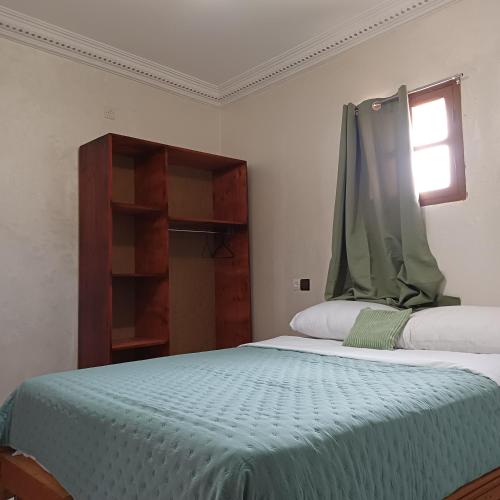 a bedroom with a bed with a green blanket on it at La Belle Vue Guest House in Aït Ben Haddou