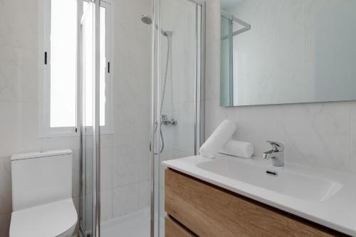 a white bathroom with a sink and a shower at La Brisa de Pilar in El Mojón