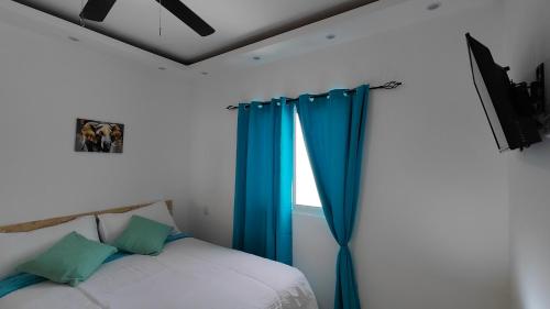 a bedroom with a bed with blue curtains and a window at Azure Breeze Hotel in Bayahibe