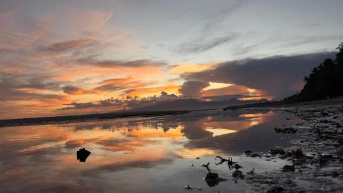 a reflection of a sunset in a body of water at Nowhere Siqujor Hostel in San Juan