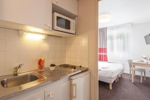 eine Küche mit einem Waschbecken und ein Zimmer mit einem Bett in der Unterkunft Appart'City Classic Lyon Part Dieu Garibaldi in Lyon