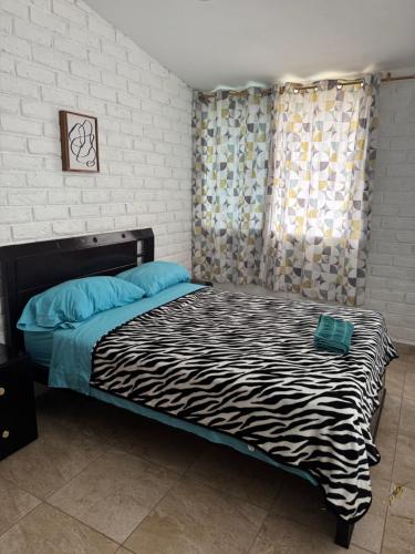 a bed in a room with a zebra patterned blanket at Palmerai BUCAY in Cumanda