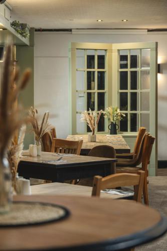 a dining room with tables and chairs and windows at Inn For All Seasons in Redruth