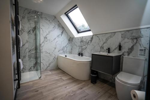 a bathroom with a tub and a toilet and a sink at FAMILY FRIENDLY, HOT TUB, Fire Pit, Spacious & Modern in Fochabers