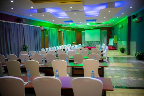 a conference room with tables and chairs and a screen at Tiffany Diamond Hotels Ltd - Indira Gandhi street in Dar es Salaam
