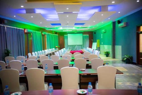 a conference room with tables and white chairs at Tiffany Diamond Hotels Ltd - Indira Gandhi street in Dar es Salaam