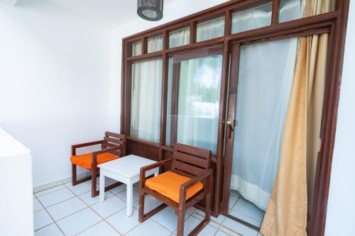 a balcony with two chairs and a table and a window at The Safiya Hotel, Diani Beach in Diani Beach