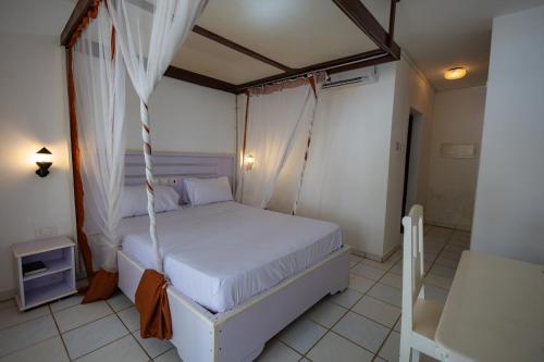 a bedroom with a white bed with a canopy at The Safiya Hotel, Diani Beach in Diani Beach