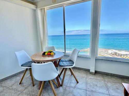 a table and chairs in a room with a view of the ocean at Direct at the beach - Arguineguin in Arguineguín