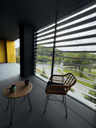 a room with a chair and a table and a large window at Aurum Apartman Harmónia a komfort v centre Bardejova in Bardejov