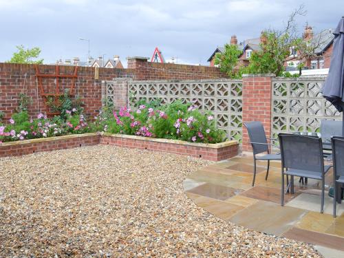 a patio with chairs and flowers on a fence at Amazing Cottage In Filey With 3 Bedrooms And Wifi in Filey