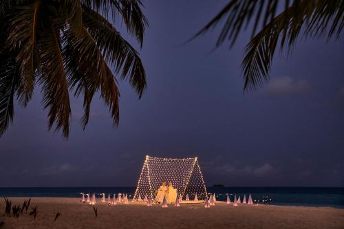 a group of people standing on a beach with a lit upescription at ROBINSON MALDIVES - Adults only in Gaafu Alifu Atoll