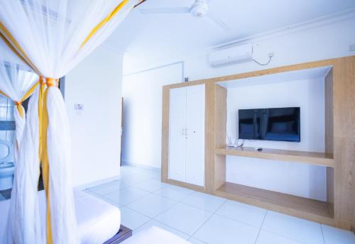 a living room with a tv and a curtain at The Safiya Hotel, Diani Beach in Diani Beach