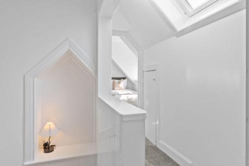 a white staircase with a mirror in a room at Kirkstyle Cottage in Coatbridge