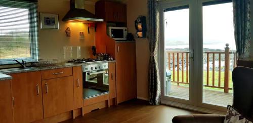 a kitchen with a stove top oven next to a balcony at MacKenzies Bothy - SeaFront Cabin in Broadford