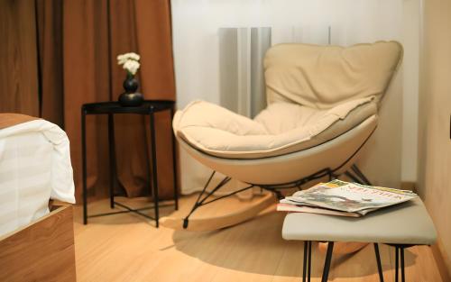 a bedroom with a chair and a table with a magazine at Rooms Apart Hotel by RED in Yerevan