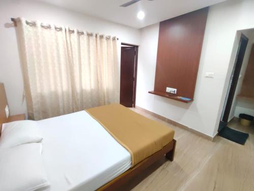 a bedroom with a white bed and a wooden floor at Nandan Residency in Mysore