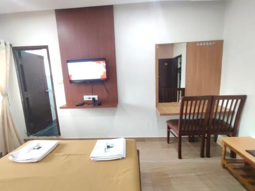 a room with a table and a tv and a chair at Nandan Residency in Mysore