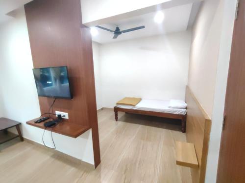 a small room with a bed and a tv at Nandan Residency in Mysore
